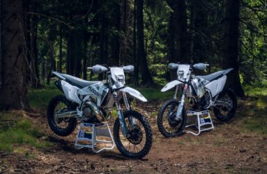 A Husqvarna TE300 Pro and an FE350 side by side in a forest.