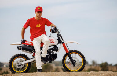 Greg Sigaud wearing a red shirt and white pants, sitting on a YCF Sunday X187 model.